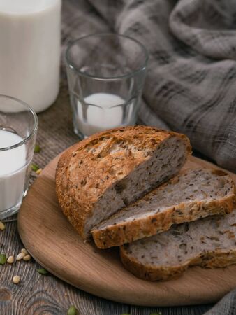 Breakfast in the country with milk and whole wheat bread. Sliced bread on an old vintage planked wooden table with canvas.の写真素材