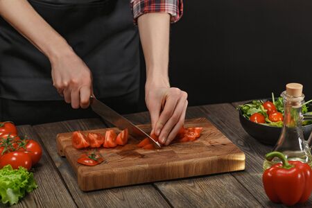 Woman cooking fresh salad. Female hands cutting vegetables on board on wooden table.の写真素材