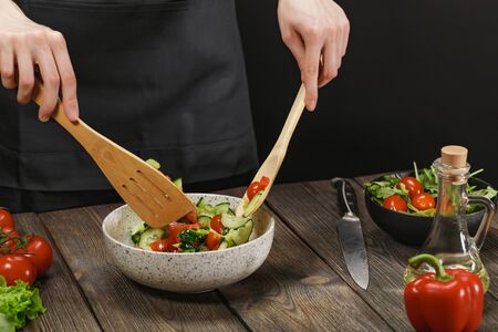 Woman cooking fresh healthy vegetable salad on wooden table. Diet concept for healthy lifestyle.の写真素材