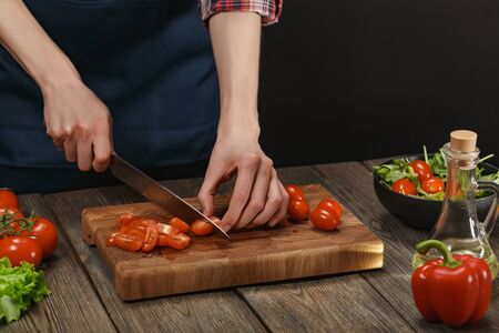 Woman cooking fresh salad. Female hands cutting vegetables on board on wooden table.の写真素材