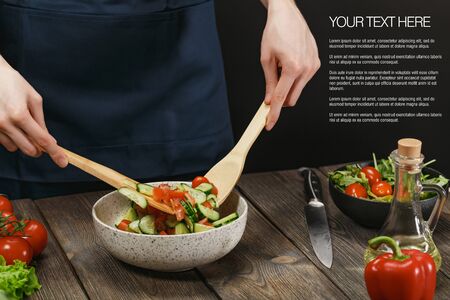 Woman cooking fresh vegetable salad on wooden table. Healthy vegetarian lifestyle.の写真素材
