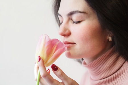 Beautiful brunette woman sniffing tulipの写真素材