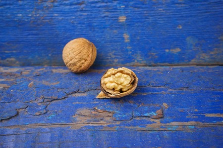 Walnuts on a blue wooden background. Walnut kernels and whole walnuts on blue boardの写真素材