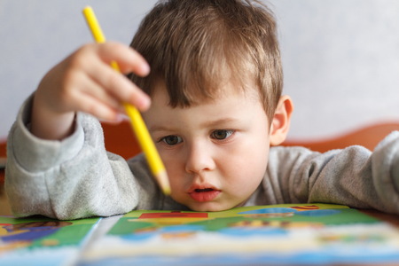 Little boy drawing with color pencils. Cute boy sitting at table and drawingの写真素材