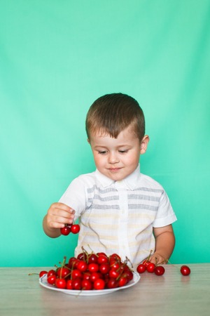 Cute boy boy eating ripe cherries.の写真素材