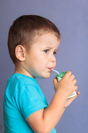 Small beautiful boy drinking juice from straw. Concept for healthy lifestyles or healthy kidの写真素材