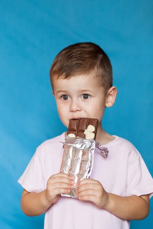 Cute Little Boy Eating Chocolate Bar. Very cute kid with chocolate, isolated.の写真素材