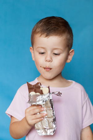 Cute Little Boy Eating Chocolate Bar. Very cute kid with chocolate, isolated. Happy boy with chocolate barの写真素材