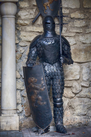 Ukraine, Lviv - October 4, 2018. Knight in full armor with a sword against the background of the ancient walls of a stone castle. Suit of knight armourのeditorial素材