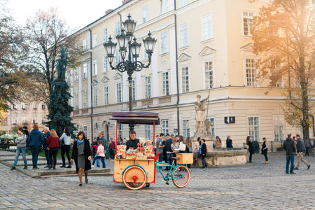 LVIV, UKRAINE - OCT 31, 2018: Tourists resting near a fountain of Adonis. Bike sweets Lviv. The Market Square.のeditorial素材