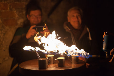 LVIV, UKRAINE - December 2, 2018. Tourists watch the preparation of extreme coffee. Caramelized coffee. Fire show.のeditorial素材