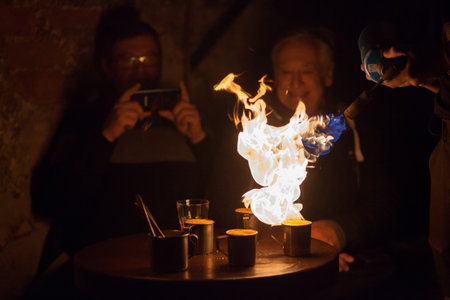 LVIV, UKRAINE - December 2, 2018. Tourists watch the preparation of extreme coffee. Caramelized coffee. Fire show.のeditorial素材