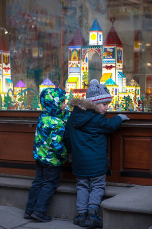 Ukraine, Lviv - December 6, 2018. Two little boys on a Lviv street looking at shop window decorated for Christmasのeditorial素材
