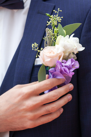 Groom in a suit holding buttonhole. Wedding accessoriesの写真素材