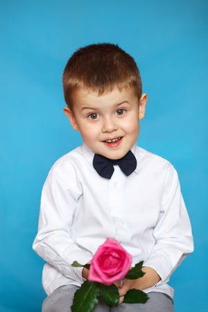 A cute little boy holds a flower in his hand.