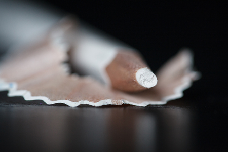 White pencil and shavings on black background. Selective focus.の写真素材