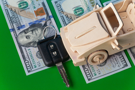 Wooden Toy Car and key vehicle with money on green background. Concept of sale and. Currency, savings.の写真素材