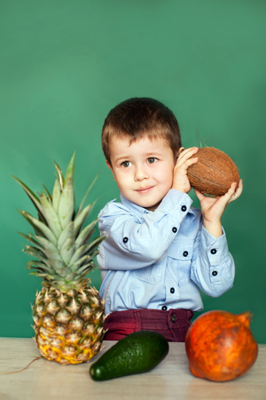 Cute little boy holding coconut on green background. Concept healthy eating.の写真素材