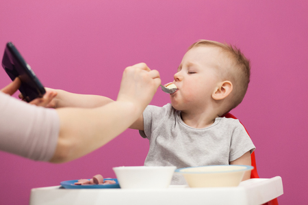 Little boy does not want to eat Mashed potatoes. Mom feeds her beautiful baby with a spoon.の写真素材
