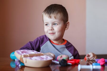 Cute little boy playing with many-colored plasticine. Boy playing with toys Dental Tools. Facial...