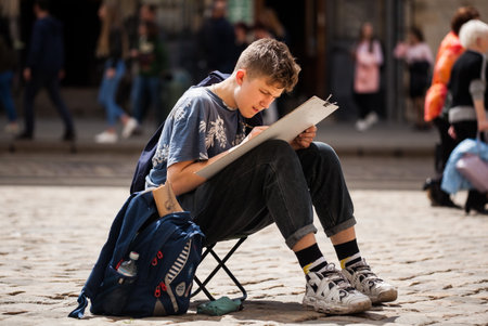 LVIV UKRAINE - May 17, 2019: Boy create outdoors sketches. Learner paint the urban landscape of the old European city. School Art Workshopsのeditorial素材