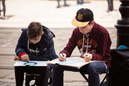LVIV UKRAINE - May 17, 2019: Two boys create outdoors sketches. Children learn to paint outdoors. School Art Workshopsのeditorial素材