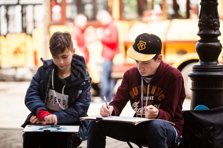 LVIV UKRAINE - May 17, 2019: Two boys create outdoors sketches. Children learn to paint outdoors. School Art Workshopsのeditorial素材