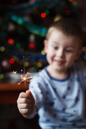 Beautiful Little child holding burning sparkler on New Years Eve, bengal fire. Select focus on fireworks.の写真素材