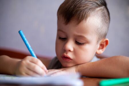 Closeup portrait of cute little boy drawing picture. The beautiful, emotional face of a child of...