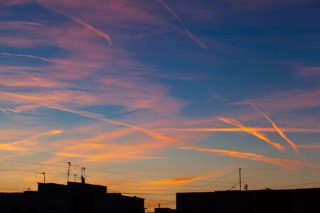 Traces of aircraft in the sky at sunset. Television antennas on the building roofs at sunset. Plane...