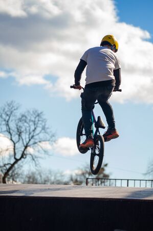 Young man doing tricks on a BMX bike. BMX freestyle against the backdrop of urban landscape. Extreme sports is very popular among youth. Concept of sports accessories.の写真素材