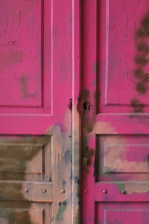 Locked wooden old door, pink, ruined, peeling color Ethnic styleの写真素材