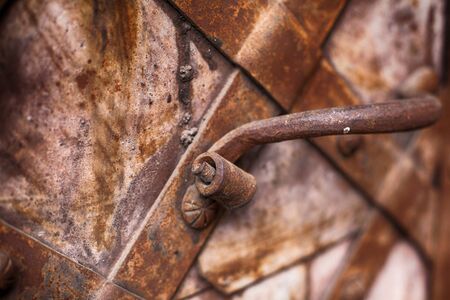 Forged handle on the background of metal doors. Fragment of the old iron doorの写真素材