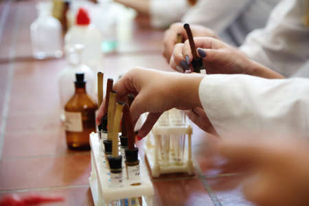 Girl students conducting scientific experiment in chemistry laboratory classroom. Close up hand...