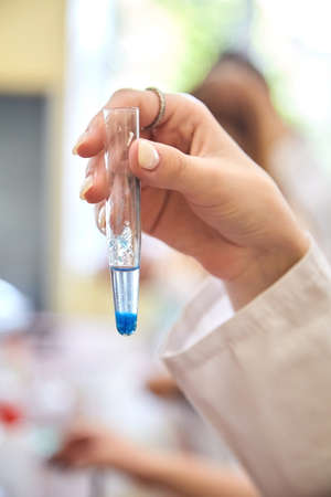 Girl students conducting scientific experiment in chemistry laboratory classroom. Close up hand...