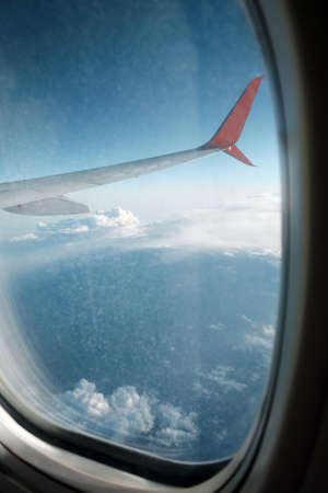 Window of the Illuminator in the plane. Look at the clouds and the wings of an airplane through the...