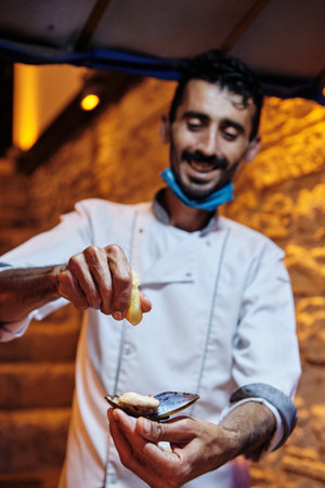 Kusadasi, Turkey - 07.22.2021: Man selling raw mussels in shells served with lemon juice. Streets of Kusadasi. Kusadasi night life. Turkey vacationのeditorial素材