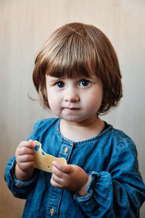 Little baby girl eating cheese. Cute baby enjoy a piece of cheeseの写真素材