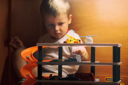 Little boy playing toy cars. Child driving car to parking garage. Kids at home. Selective focus on carsの写真素材