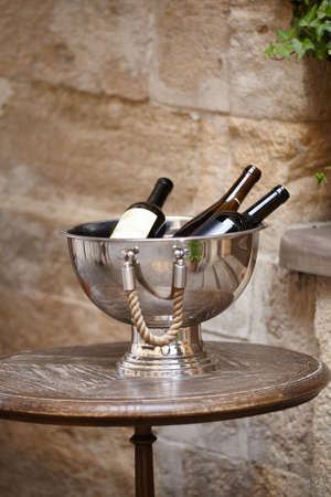 Wine bottles in a Large metal bowl standing on wooden table on the city street to attract visitors to the restaurant. Wine accessoriesの写真素材