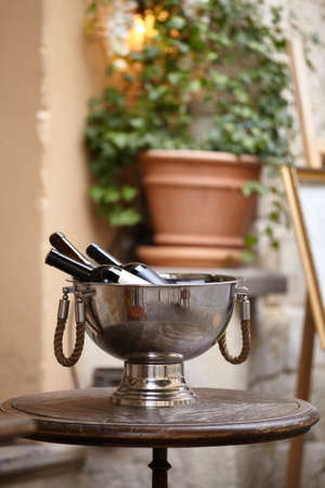 Wine bottles in a Large metal bowl standing on wooden table on the city street to attract visitors to the restaurant. Wine accessoriesの写真素材