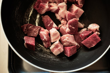 Pork meat in a frying pan is cut by large cubes. Frying Pork. Close up viewの写真素材