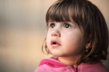 Portrait of a little two-year-old girl with a focused gaze. A small child looks to the left.の写真素材