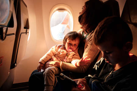 Family of mother, child and baby traveling sitting in the seats of an airplane. Happy family trip conceptの写真素材