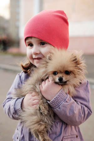 Beautiful baby girl with sweet dog. Child and small dog Pomeranian Spitz. Pet Lover Concept. Selective Focus Photo Of Dogの写真素材