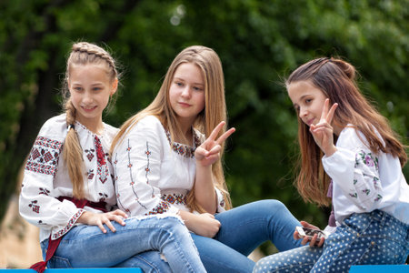 Lviv, Ukraine - May 19, 2021: Three teenagers girls in embroidery show a sign of freedom....