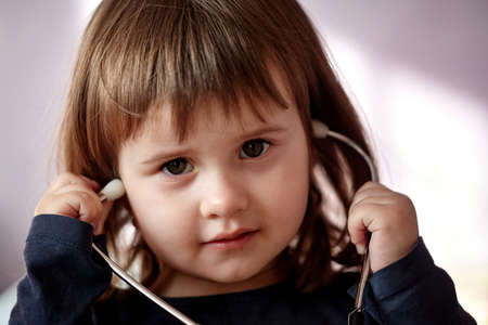 little girl playing with stethoscope. Close up portrait of cute little Caucasian girl childの写真素材