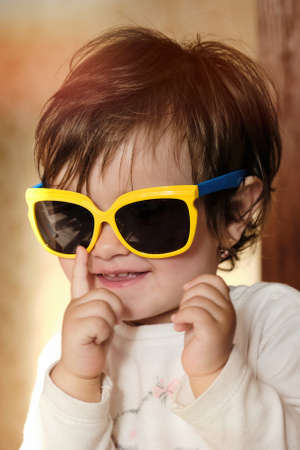 Cheerful little smiling girl in summer sunglasses. Glasses with Yellow Frame with Blue Temple.の写真素材