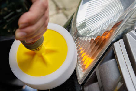 Hands of a professional car service male worker with orbital polishing machine. Car detailing, concept of details and polishing cars.の写真素材