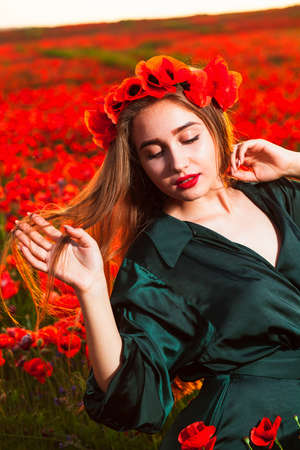 Tender girl with poppies in her hair. Romantic teen girl portrait with wreath on head enjoying in poppy flowers nature backgroundの写真素材